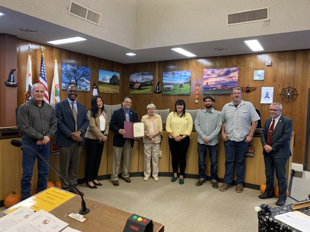 9 people stand in front of a board room