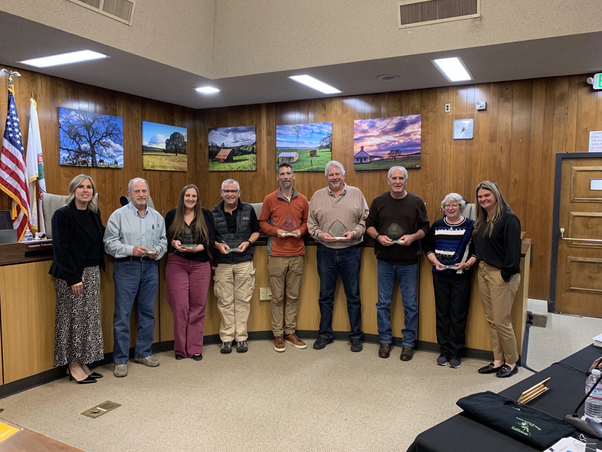 Council Members standing in front of a board room, each holding up an award